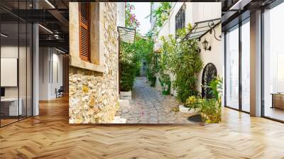 Narrow street in old european town in summer sunny day. Beautiful scenic old ancient white houses, cafe and shops with green plants. Popular tourist vacation destination, mediterranean architecture Wall mural