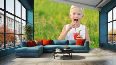 Happy laughing boy holding a glass of red fresh juice watermelon. Summer time. Healthy lifestyle Wall mural