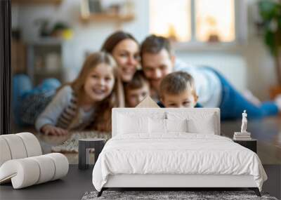 Little wooden house on floor of cozy room with happy family looking at the house in background Wall mural