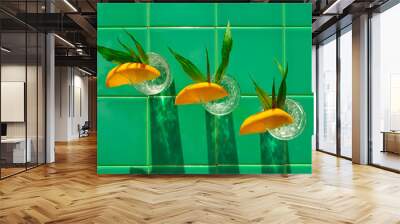 Refreshing lemonade drink in crystal glasses leaves orange slice on green tile background shadows. Sweet cold natural cocktail hot summer day. Soda water fruits berries mint tonic. Party menu vacation Wall mural