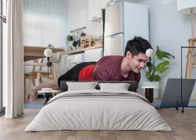 Asian handsome active young man doing exercise on floor in living room Wall mural