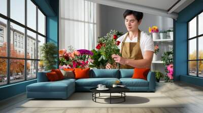 Asian handsome florist man completing beautiful bouquet in flower shop.  Wall mural