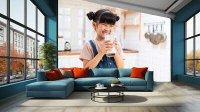 Asian little young girl drinking milk in the kitchen with smiling face Wall mural