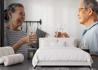 Asian senior elderly couple drink a glass of water in kitchen at home.  Wall mural