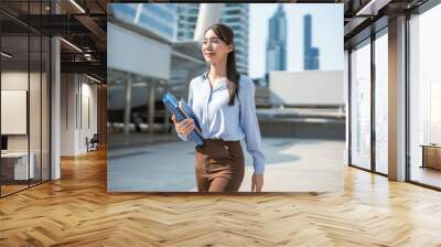 Asian young beautiful businesswoman walking outdoors in modern city.  Wall mural