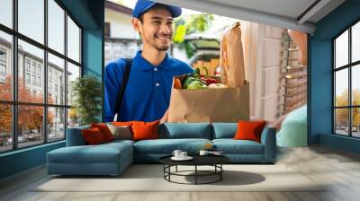 Asian young delivery man delivering package to female customer at home.  Wall mural