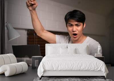 Asian young man overworking and using mobile phone check news at night.  Wall mural