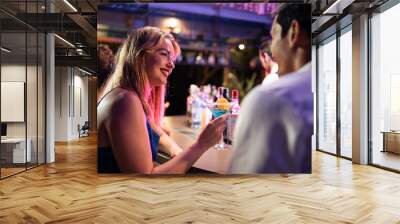 Beautiful young couple having fun, drinking alcohol cocktail in a bar.  Wall mural