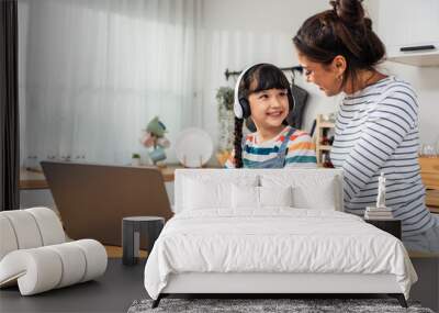 Caucasian young girl kid learning online class at home with mother.  Wall mural