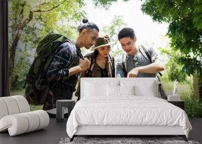 Group of Asian backpacker people using phone travel in forest together Wall mural