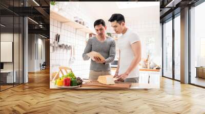 LGBT, happy Asian gay couple cooking food together in kitchen. Wall mural