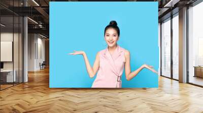 Portrait of Asian beautiful young woman show both hands with open palms on upper side with smile face. Girl presenting and advertising comparison and balance. Advertisement & presentation concept. Wall mural