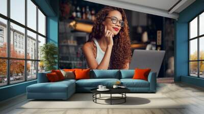 Black woman, working at cafe on laptop and remote work online as digital freelance employee. Modern professional businesswoman, writing web design blog and internet connection to work at coffee shop Wall mural