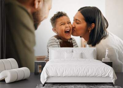 Happy boy getting a kiss by caring mother, bonding and laughing during family time at home. Young parents sharing a sweet moment of parenthood with their playful child, relaxing and carefree together Wall mural