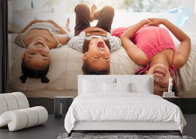 Silly kids playing upside down on bed enjoy and having fun together in parents bedroom. Happy children or siblings bonding and enjoying childhood together at cozy, warm and comfortable family home Wall mural