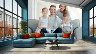 Parents, girls and smile on sofa in portrait at home for bonding, support and care in England. People, family and happy with kids on couch in living room to relax or chill for child development Wall mural