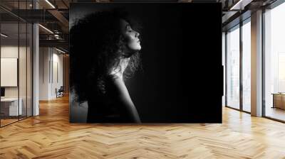 beautiful girl with curly hair on a black background looking to the side, her eyes closed, black and white photo Wall mural