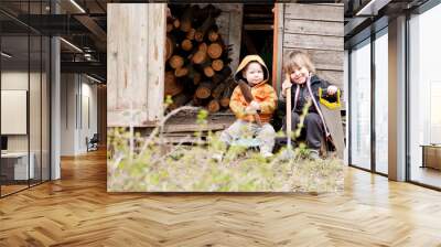 Two little children sit near a shed with garden tools Wall mural