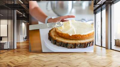 woman icing vanilla cake with metal spatula  Wall mural