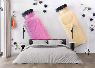 Smoothies with berries and fruits in two glass bottles on the white table. Healthy drink variation and kids food. Flat lay Wall mural