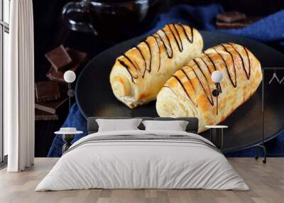 Two golden buns decorated with chocolate on a dark plate Wall mural