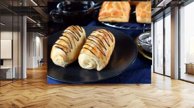 Two golden buns decorated with chocolate on a dark plate Wall mural