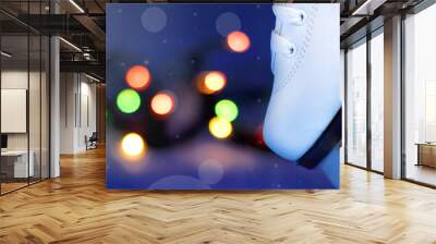 White ice skate shoe standing on the blade against the blurred Christmas lights. Copy space. Ice skating in the night rink. Winter holidays pastime activity Wall mural