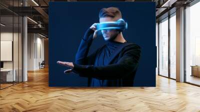 Guy using VR helmet scrolling invisible screen while interacting with virtual reality. Blue neon light. Augmented reality, future technology, game concept. Black minimalism. Wall mural