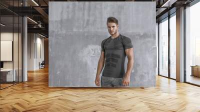 Muscular model in fashion sportswear on urban gray background. Portrait of brutal  strong guy with a modern trendy hairstyle. Sports young man working out outdoor. Wall mural