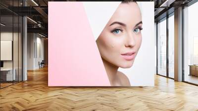 Portrait of young beautiful woman with healthy glow perfect smooth skin look into the hole of colored paper. Model with natural nude make up. Fashion, beauty, skincare, cosmetology concept. Wall mural