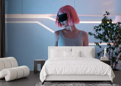 Woman in futuristic costume. Female in modern VR glasses interacting with network while having virtual reality experience. Augmented reality game, future technology, AI concept. VR. Neon blue light. Wall mural