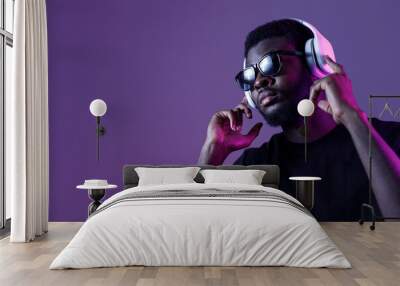 Young African American man in sunglasses and headphones listens to music and dances. Wall mural