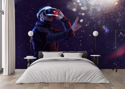 Young man over dark magic light background. Guy in glasses of virtual reality. Augmented reality, game, hobby concept. VR. Wall mural