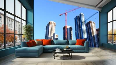 Tall modern skyscrapers with cranes in a city skyline against a blue sky construction concept Wall mural