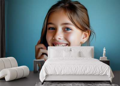 Cheerful girl chatting on the phone against a vibrant blue backdrop Wall mural