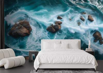 Dynamic aerial view of crashing waves on rocky ocean surface showcasing turbulent sea patterns and the beauty of nature during daytime Wall mural