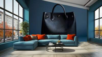 Elegant black leather handbag with top handle against a dark blue backdrop Wall mural