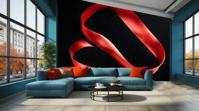 Elegant red ribbon gracefully curled in S shape against deep black background Wall mural