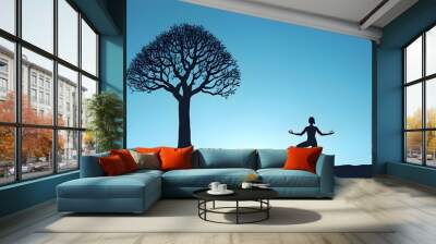 Graceful silhouette of a woman in yoga tree pose, embodying balance and serenity against a calming blue background Wall mural