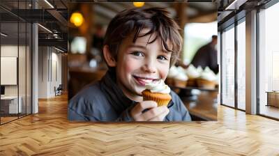 Joyful boy savoring a delicious cupcake in a charming rustic cafe Wall mural