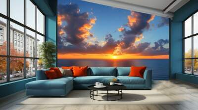 panoramic view of the ocean and sky illuminated by orange hues at sunset with dramatic clouds reflecting evening light Wall mural