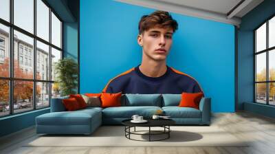 Stylish young male model in autumn-themed sweatshirt against a vibrant blue backdrop Wall mural