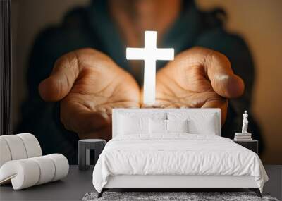 Symbol of healing and hope: a glowing white cross held in open hands against a peaceful, soft backdrop. Wall mural