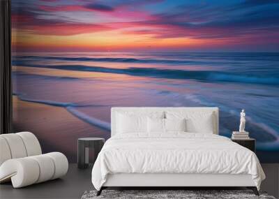 Tranquil beach at dusk with gentle waves caressing smooth sands beneath a vibrant, colorful sky Wall mural