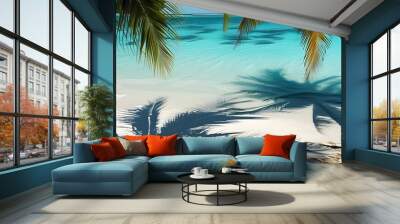 Tropical paradise with palm shadows dancing on shimmering water over pristine white sand beach Wall mural