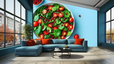 Vibrant Fresh Summer Salad with Cherry Tomatoes, Spinach, and Pomegranate against a Light Blue Background Wall mural