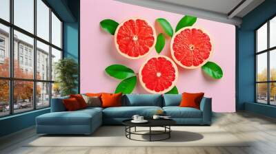 Vibrant grapefruit slices with green leaves on a soft pink backdrop, offering a refreshing and juicy appeal. Wall mural