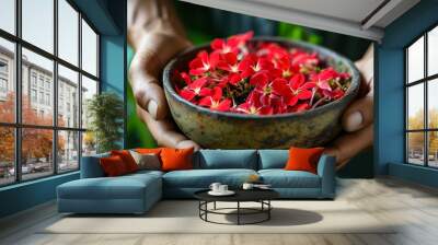 Vibrant red flowers in a rustic bowl against a backdrop of blurred greenery Wall mural