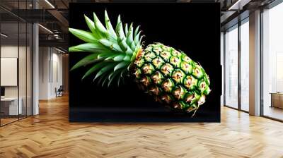 Vibrant ripe pineapple with lush green crown against a striking black backdrop Wall mural