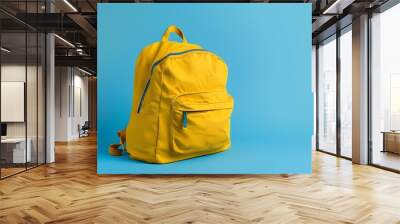 Vibrant yellow backpack against bright blue background symbolizing new beginnings, education, adventure, travel, and preparedness Wall mural